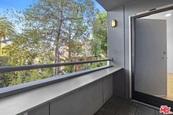 View from a balcony with railing and visible trees.