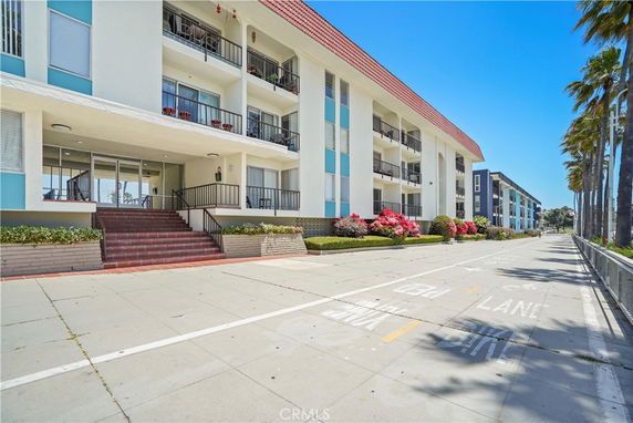 Front view of a multi-story building with a red-tiled roof and balconies.