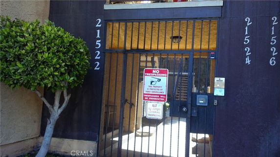 Entrance view of a multi-unit building with gated entry and visible unit numbers.