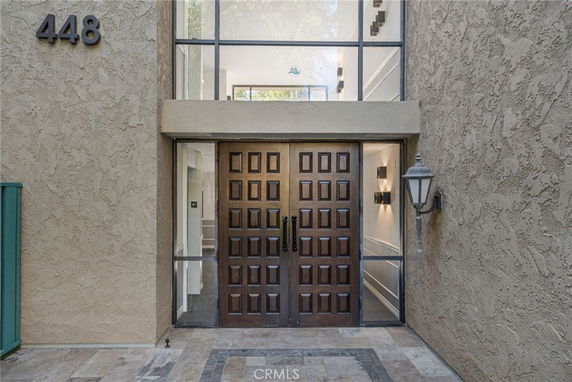 Front view of a building's entrance with a wooden double door and glass panels.