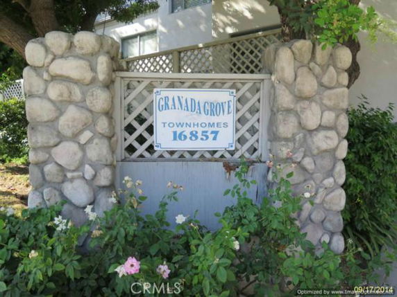 Front view of a building entrance with stone pillars and a sign.