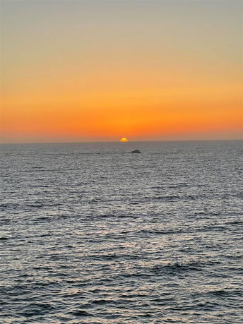 Sunset over the ocean with a boat in the distance.
