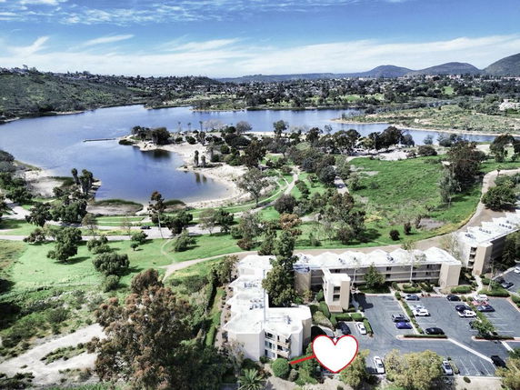 Panoramic view of residential buildings near a lake with surrounding greenery.