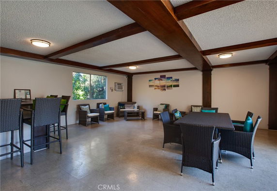 Indoor recreational area with wicker furniture and a window, decorated with a beach scene painting.
