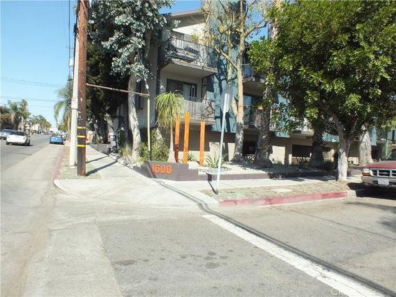 Front view of a multi-story building with balconies and a street view.