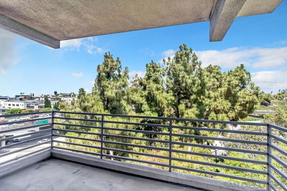 View from a building's balcony overlooking trees and distant buildings.