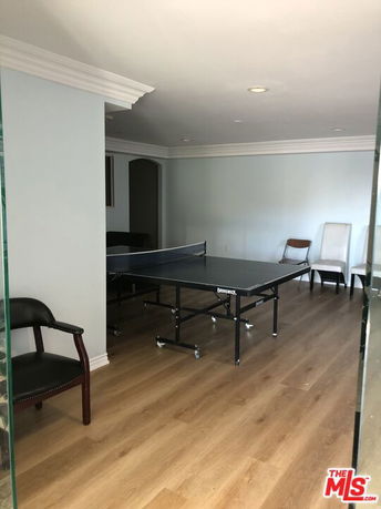 Indoor room with a table tennis setup and chairs along the wall.
