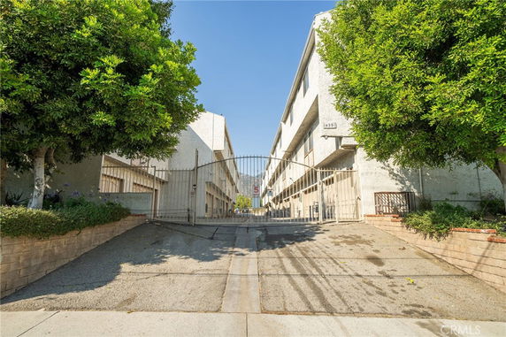 Front view of a multi-story apartment building with a gated entrance.
