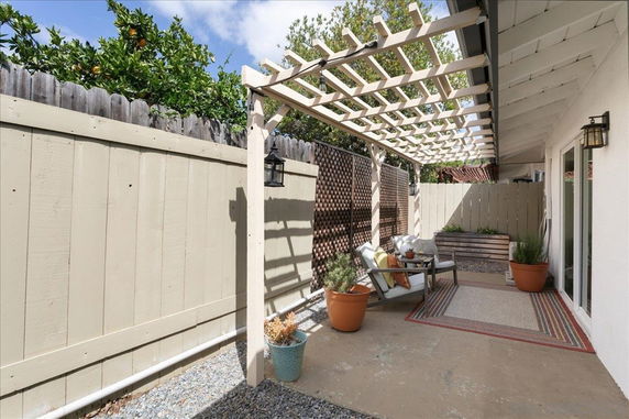 Outdoor patio area with a wooden pergola and seating arrangement.