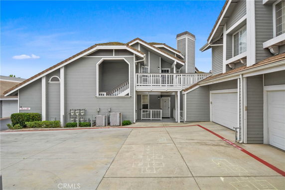 Front view of a multi-story residential building with a grey exterior and attached garages.