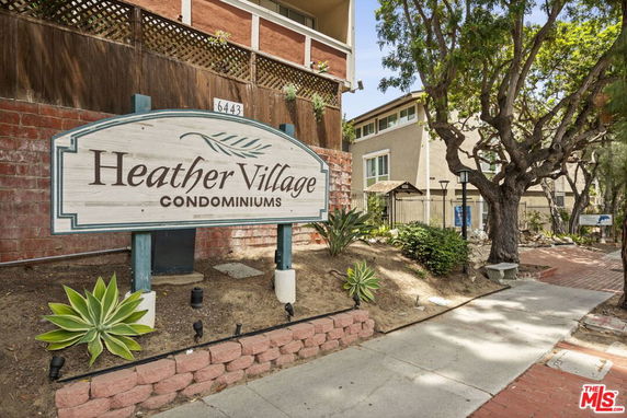 Front view of a condominium complex with a sign reading 'Heather Village Condominiums'.