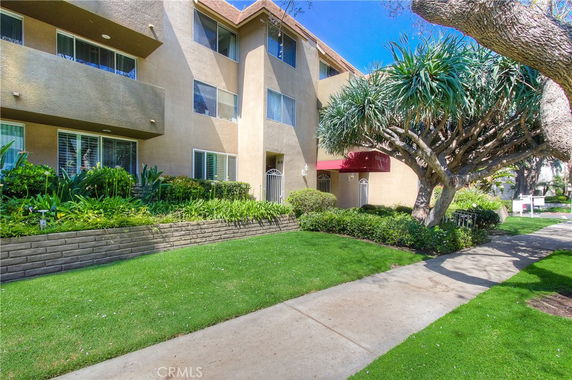 Front view of a multi-story residential building with a landscaped garden.