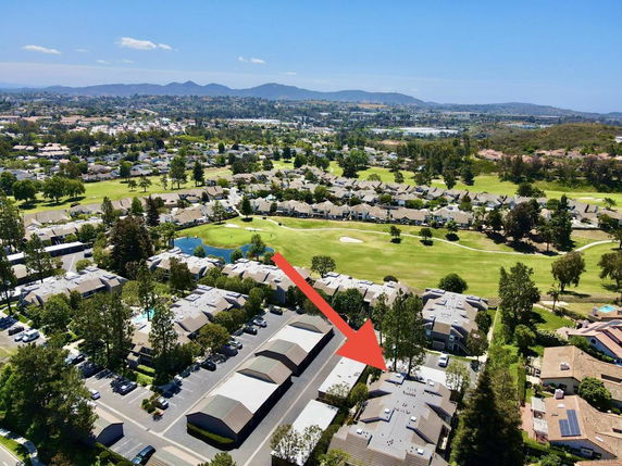 Aerial view of residential area with buildings, trees, and surrounding landscapes.