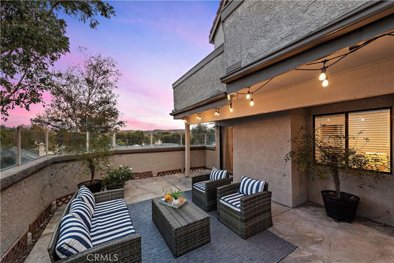 Rooftop patio area with seating and string lights at sunset.