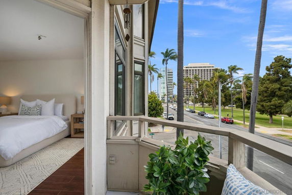 View from a balcony overlooking a street with palm trees and buildings.