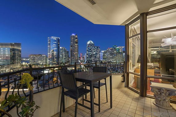 Panoramic view of city skyline from a balcony at night with modern buildings visible.