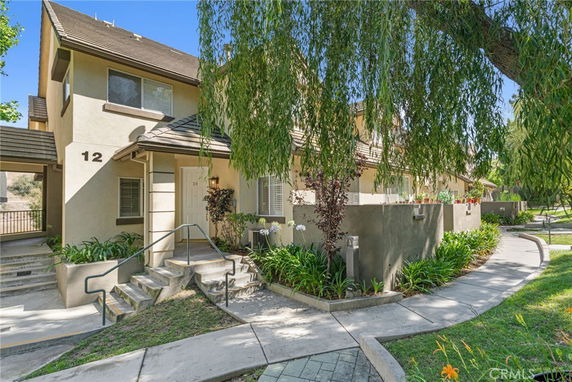 Front view of a multi-story residential building with a small garden and pathway.