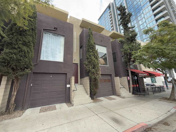 Front view of a two-story modern townhouse with large windows and a garage.