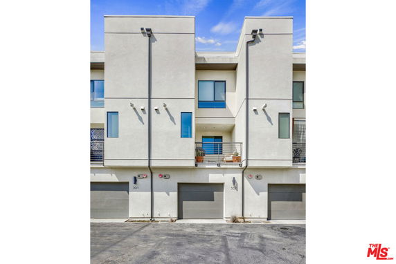 Front view of a multi-story building with garages on the ground level.