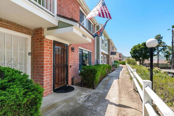 Front view of a brick townhouse with a walkway and an American flag.