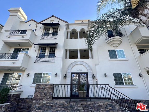 Front view of a multi-story building with balconies and decorative railings.