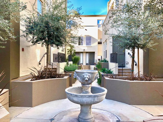 Front view of a multi-story residential building with a central courtyard and water fountain.