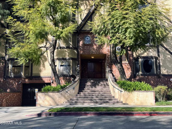 Front view of a multi-story building with brick and stucco facade and a central entrance with stairs.