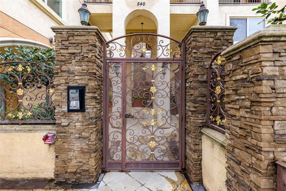 Front view of a building entrance with a decorative metal gate and stone walls.