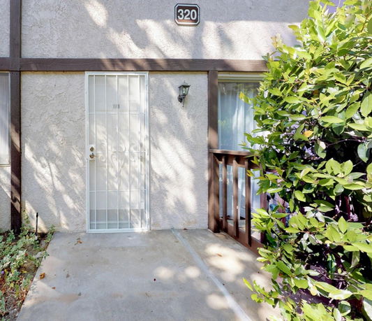 Front view of a house with a metal security door and a house number sign.