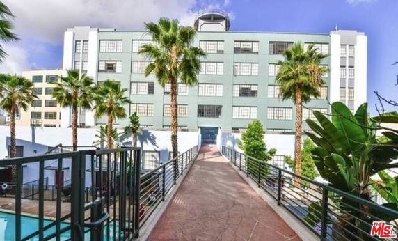 Front view of a multi-story building with large windows and a walkway leading to it.