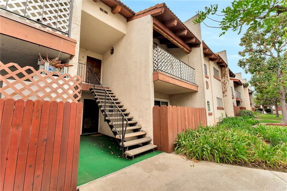 Front view of a multi-story residential building with balconies and a staircase.