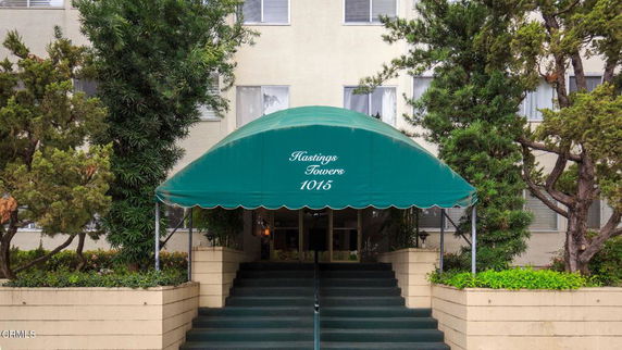 Front view of a building entrance with steps leading up to a green awning labeled 'Hastings Towers 1015'.
