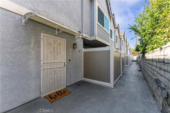 Front view of a townhouse with a metal door and adjacent walkway.