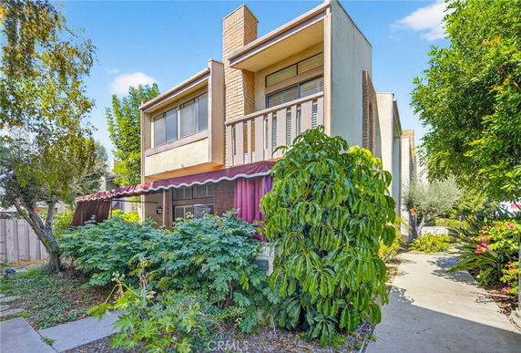 Front view of a modern two-story house with large windows and a brick chimney.