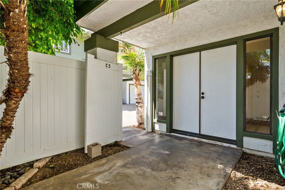 Front view of an entrance to a building with double glass doors and surrounding greenery.