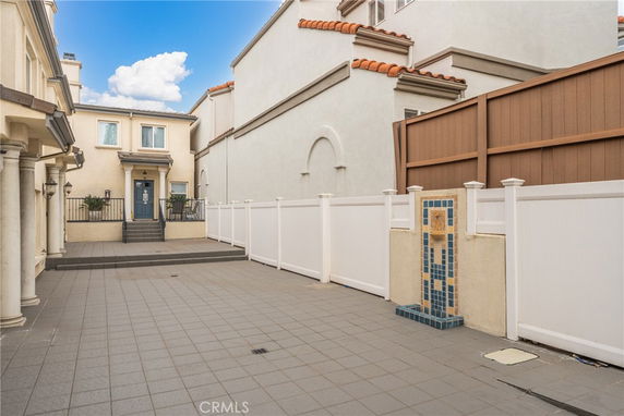 Front view of a house with an entryway and tile-paved courtyard.