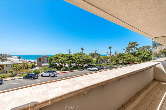 Panoramic view from a balcony overlooking a coastal area with a road and ocean in the distance.