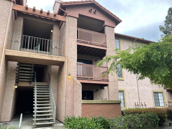 Front view of a multi-story residential building with balconies and staircase.