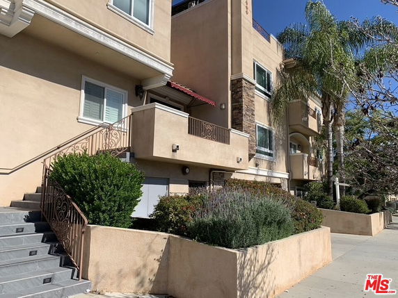 Front view of a multi-story building with beige exterior and balconies.