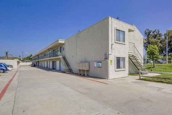 Front view of a two-story building with external staircases and parking area.
