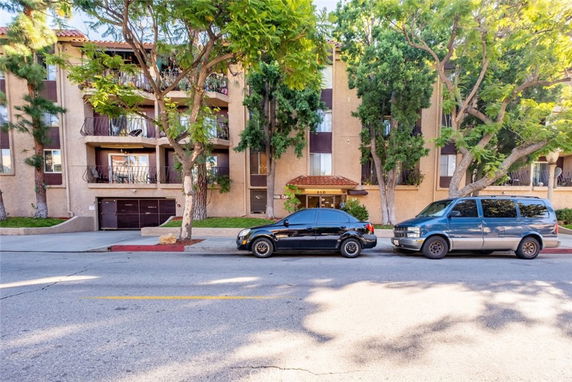 Front view of a multi-story residential building with balconies and a parking garage entrance.