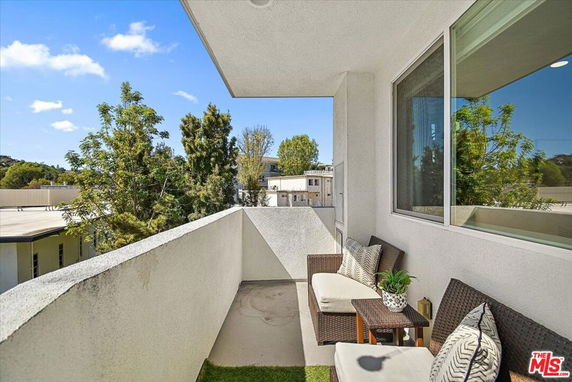 Balcony view showcasing outdoor furniture and surrounding trees.