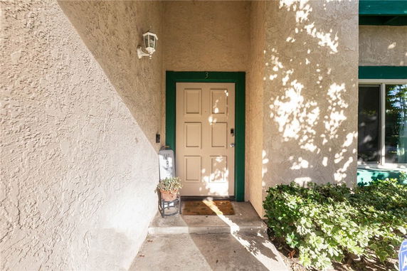 Front view of a house entrance with a green-framed door and light fixture.