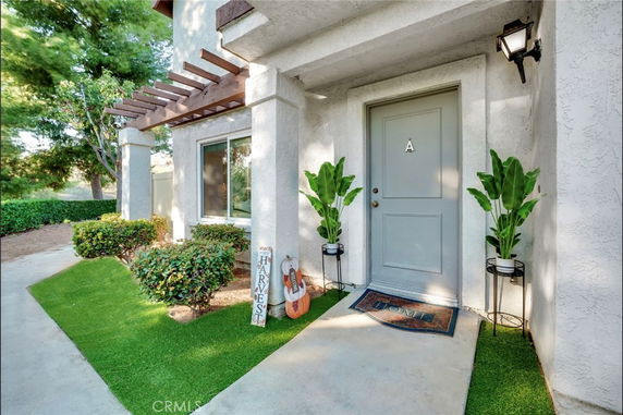 Front view of a house entrance with a door labeled 'A' and decorative plants.