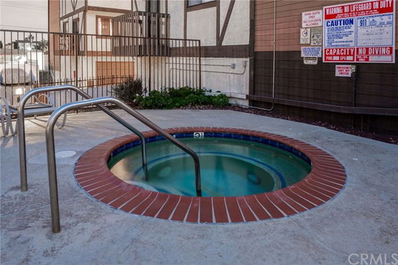 Outdoor hot tub with handrails and safety signs.