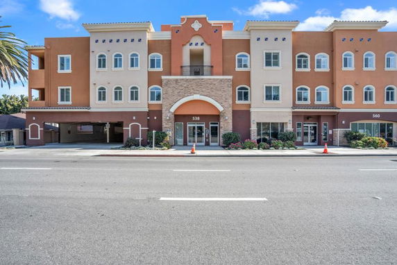 Front view of a three-story commercial and residential building with archway entrance and balconies.