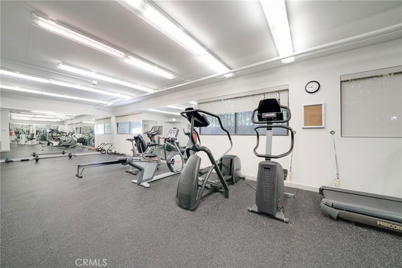 Room with various gym equipment including treadmills and exercise bikes.