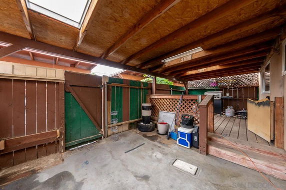 Covered outdoor parking area with wooden fencing and storage space.