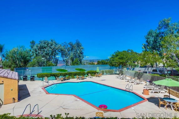 Outdoor swimming pool area with sun loungers and umbrellas.
