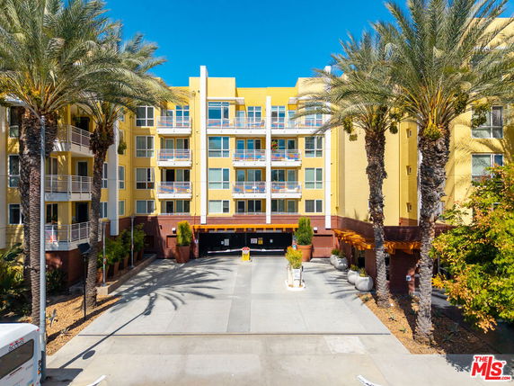 Front view of a multi-story apartment building with palm trees.